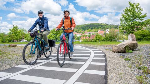 Frau und Mann fahren auf Rädern den Bahnradweg